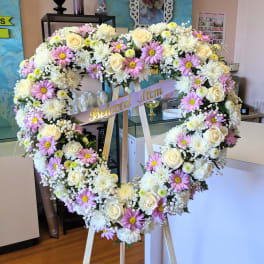 Heart-shaped floral wreath on an easel with a "Beloved Mom" ribbon