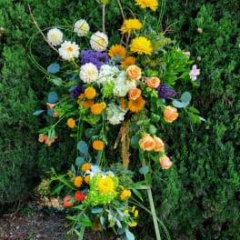 Large floral standing spray with yellow, white, orange, and purple blooms