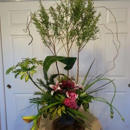 Tall floral arrangement with pink and white lilies in a dark vase