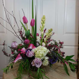Tall floral arrangement with pink tulips, lavender roses, and white hydrangea