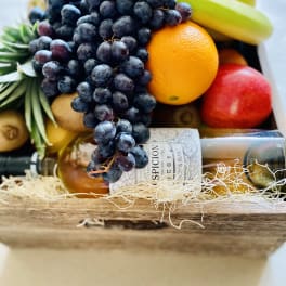 Fruit gift box with grapes, bananas, oranges, and a wine bottle
