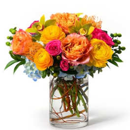 Bright orange, yellow, and pink flower arrangement in a clear glass cylinder vase with submerged branches.