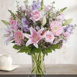 Pink roses, lilies, and gerbera daisies in a clear glass vase