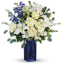 White roses and lilies with blue flowers in a tall blue vase
