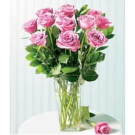 Pink roses in a clear glass vase with one rose on the table