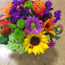 Colorful mixed bouquet with sunflower, lilies, and purple daisies