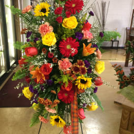 Tall standing floral spray with red, yellow, orange, and purple blooms