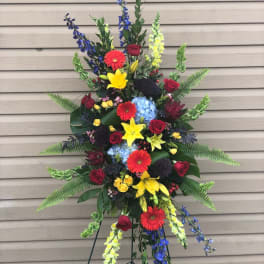 Tall standing floral spray with red, yellow, blue, and purple blooms