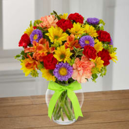 Colorful mixed bouquet in a clear glass vase with a green ribbon