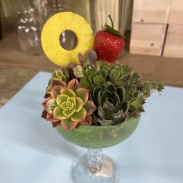 Succulent arrangement in a stemmed glass with a pineapple ring and strawberry garnish