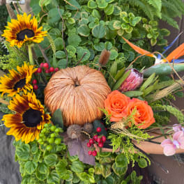 Tropical bouquet with sunflowers, orange roses, and a protea centerpiece