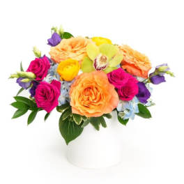 Low round arrangement of orange roses and bright mixed blooms in a white cylinder vase