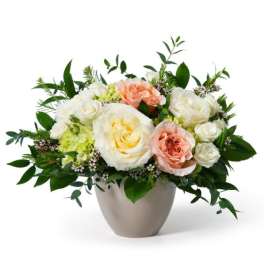 Low arrangement of white and peach roses with pale blooms in a round ceramic vase