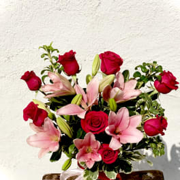 Bouquet of red roses and pink lilies in a glass vase