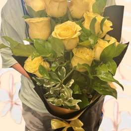 Bouquet of yellow roses wrapped in black paper with a yellow ribbon
