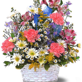 Mixed bouquet in a white woven basket with pink carnations and daisies