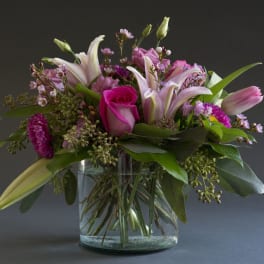 Pink lilies and roses arranged in a clear glass vase