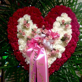 Heart-shaped floral tribute with pink and white flowers and a pink ribbon bow