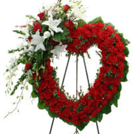 Heart-shaped red floral wreath on a stand with white flowers