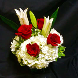 Red roses and white lilies in a compact arrangement with white hydrangeas