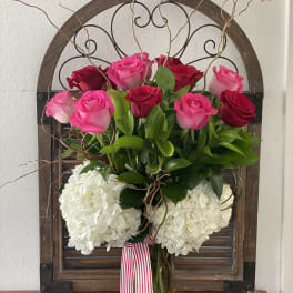 Pink and red roses with white hydrangeas in a glass vase