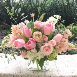 Pink tulips and roses arranged in a clear glass vase