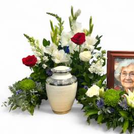 Sympathy floral arrangement with red and white roses beside a memorial urn