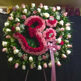 Heart-shaped floral wreath with pink and white roses and carnations, tied with a pink ribbon