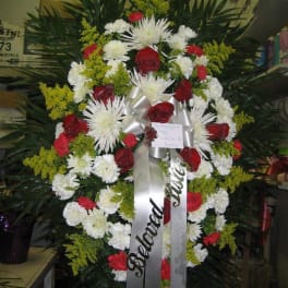 Standing funeral wreath with red and white flowers and silver ribbons
