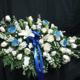 White floral spray with blue accents and a blue ribbon on a black background