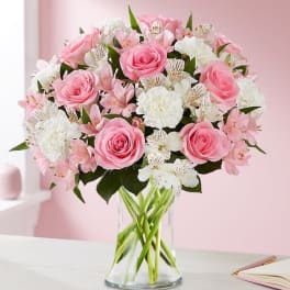 Pink roses and white flowers arranged in a clear glass vase