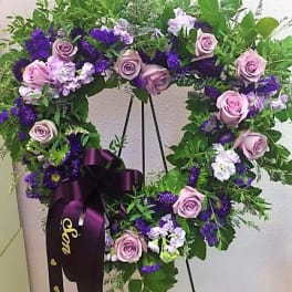 Purple and pink floral wreath on a stand with a ribbon bow