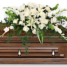 White floral casket spray on a wooden coffin