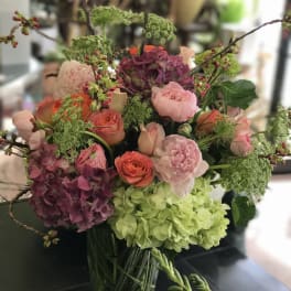 Mixed bouquet of pink, purple, and green flowers in a glass vase