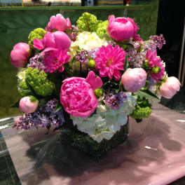 Pink and white floral arrangement in a square glass vase