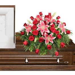Red roses and pink lilies arranged on a wooden casket