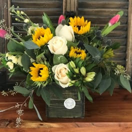 Bouquet of yellow sunflowers and cream roses in a dark box vase