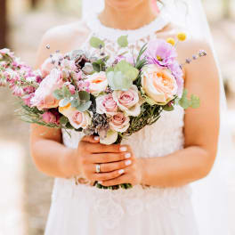 Bride holding a pastel bouquet of roses and mixed flowers