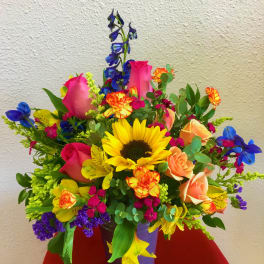 Colorful mixed bouquet in a purple vase with sunflowers and roses