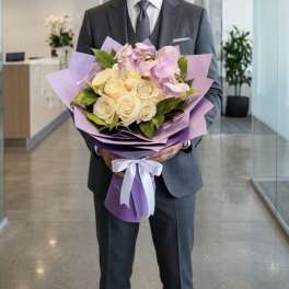 Man in a suit holding a bouquet of cream roses and pink orchids