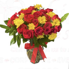 Bouquet of red roses and yellow daisies in a glass vase with a red ribbon