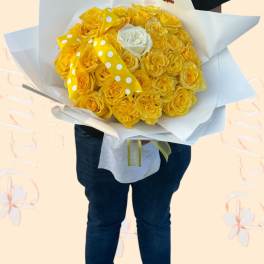 Bouquet of yellow roses wrapped in white paper with a polka-dot ribbon