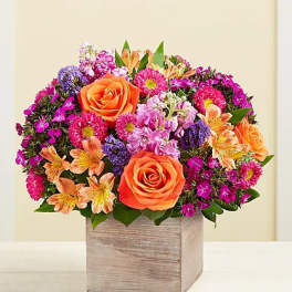 Mixed bouquet with orange roses and pink-purple flowers in a wooden box