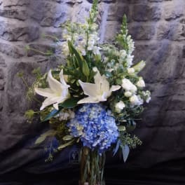 White lilies and blue hydrangeas in a glass vase