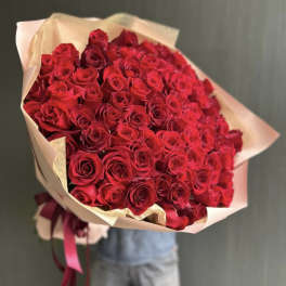 Large bouquet of red roses wrapped in pale paper
