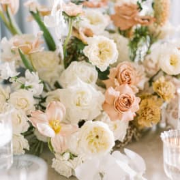 Soft peach and white floral centerpiece with orchids and roses