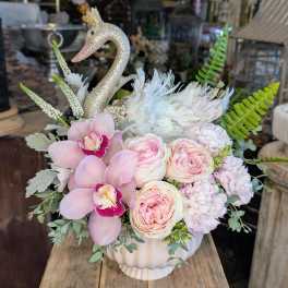 Pink floral arrangement in a white vase with a glitter swan topper