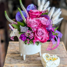 Pink and purple rose arrangement in a white unicorn planter