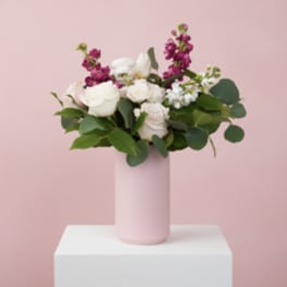 Pink and white floral arrangement in a tall pink vase