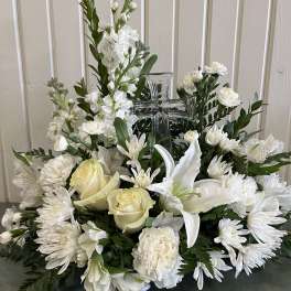 White floral arrangement with roses, lilies, and a glass cross